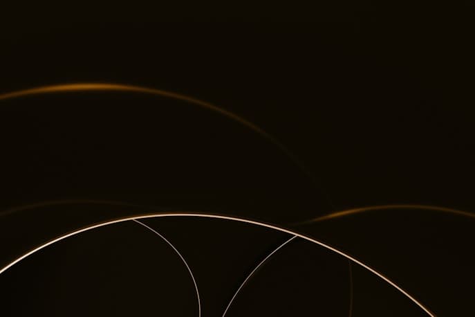 Thin golden light arcs on a dark background